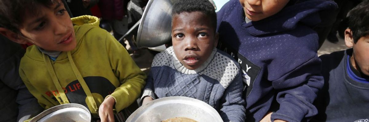Hungry Palestinian children holding pots receive food aid in Gaza