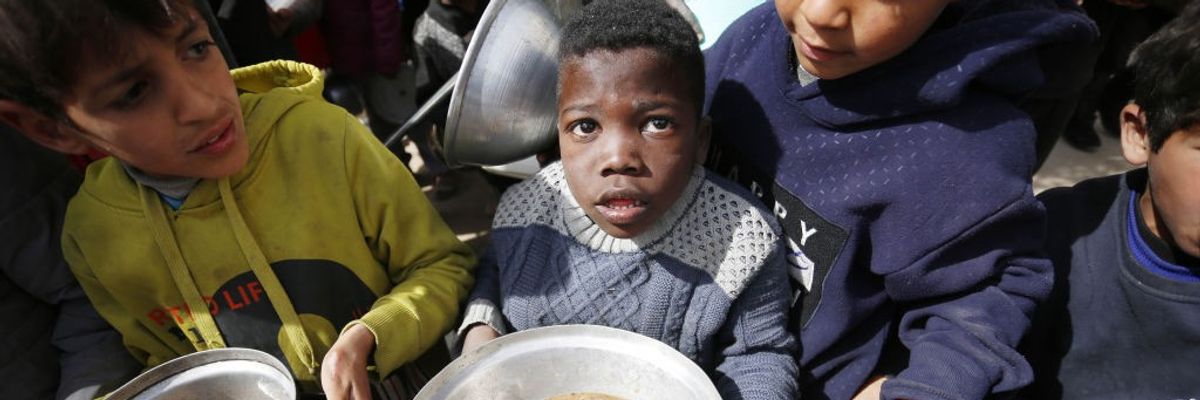 Hungry Palestinian children holding pots receive food aid in Gaza