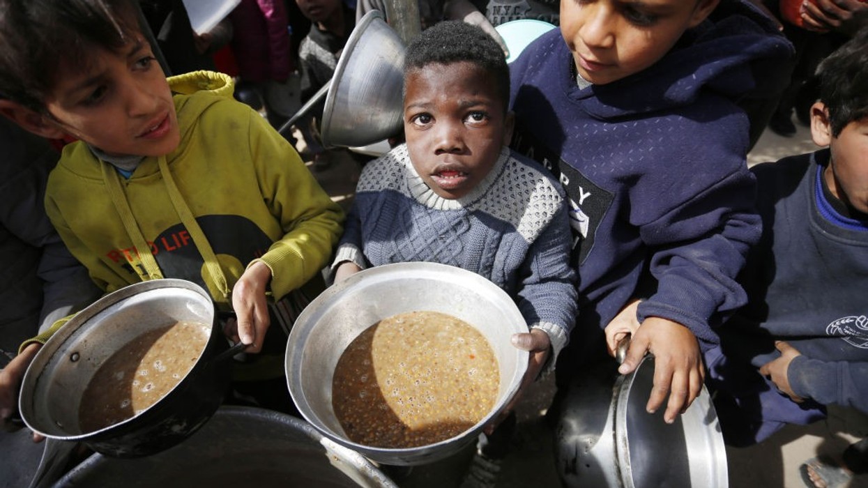 Hungry Palestinian children holding pots receive food aid in Gaza