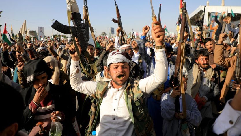 Huthi fighters brandish their weapons during a protest following US and British forces strikes, in the Huthi-controlled capital Sanaa on January 12, 2024