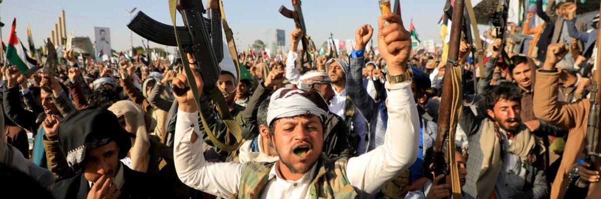 Huthi fighters brandish their weapons during a protest following US and British forces strikes, in the Huthi-controlled capital Sanaa on January 12, 2024