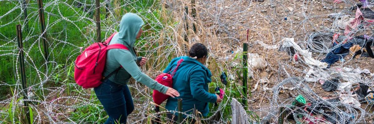 Immigrants pick through coils of razor wire