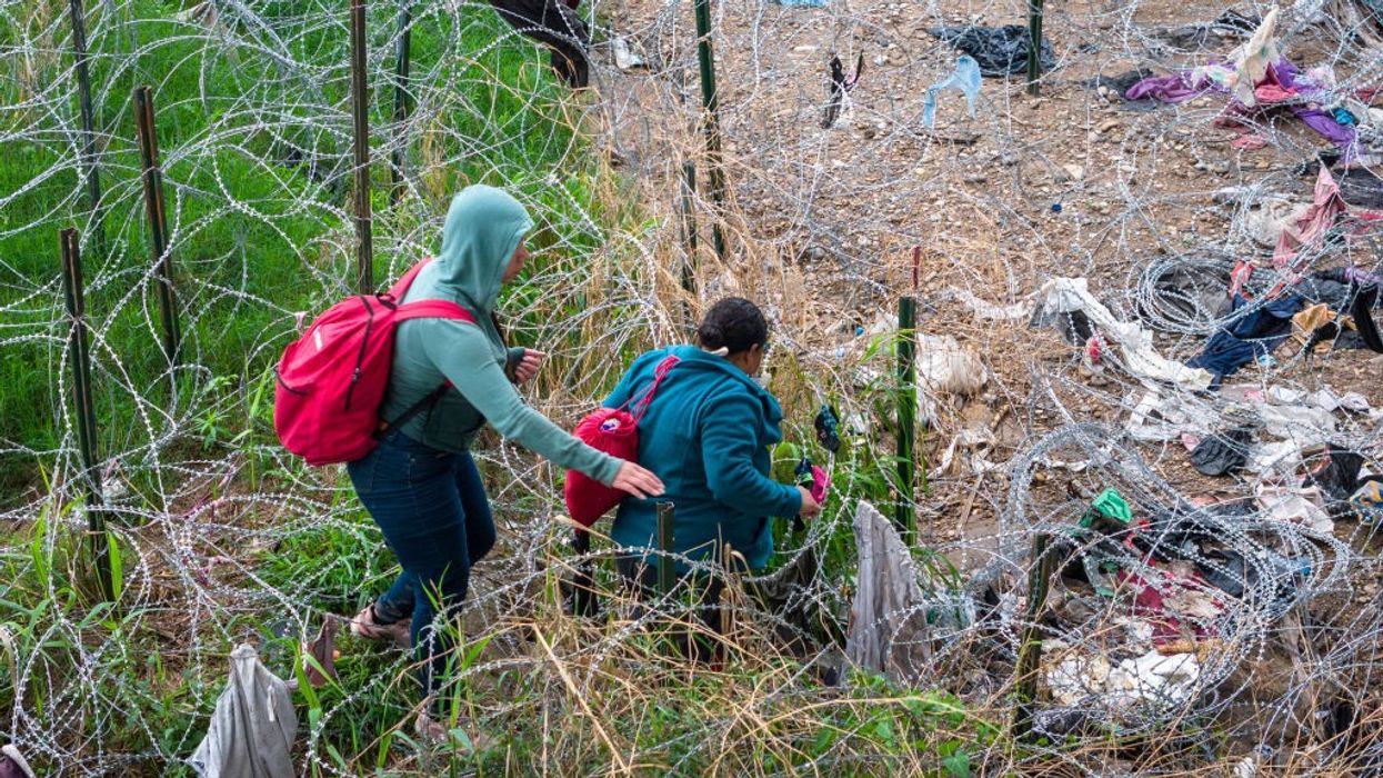 Immigrants pick through coils of razor wire