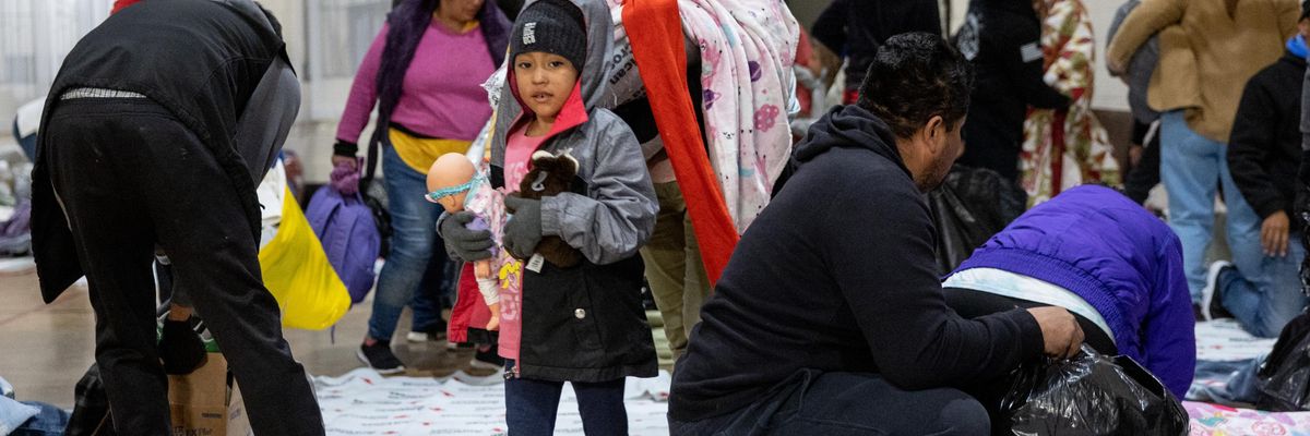 Immigrants prepare to spend the night in a gymnasium shelter