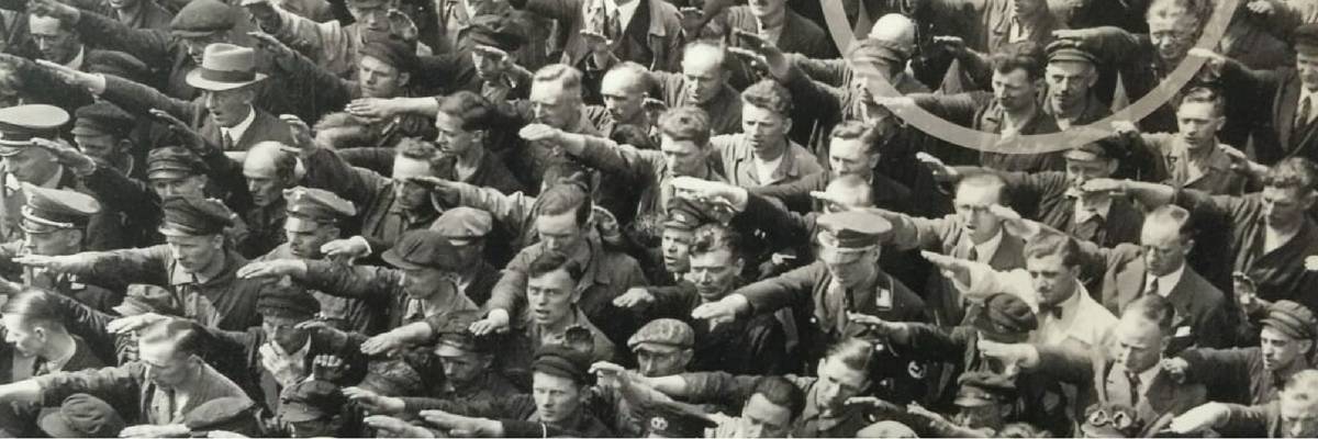 In 1930s Germany, one man stands arms crossed in a crowd of shipyard workers giving the Heil Hitler salute