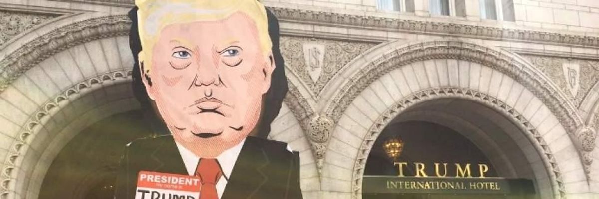 In April of 2017, a demonstrator carries a sign labeling President Donald Trump a "climate denier" outside the Trump International Hotel in Washington, D.C.