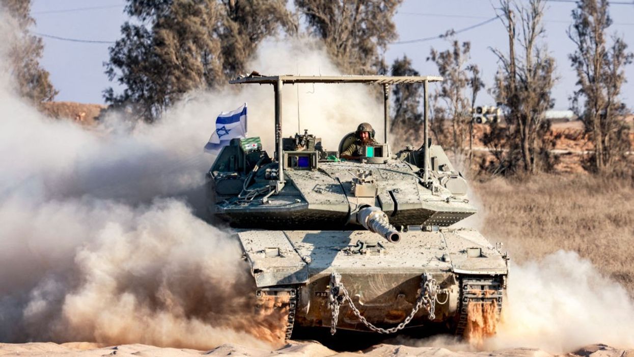 In Israeli Defense Forces tank rumbles along, kicking up dust as a soldier peers out of the turret.