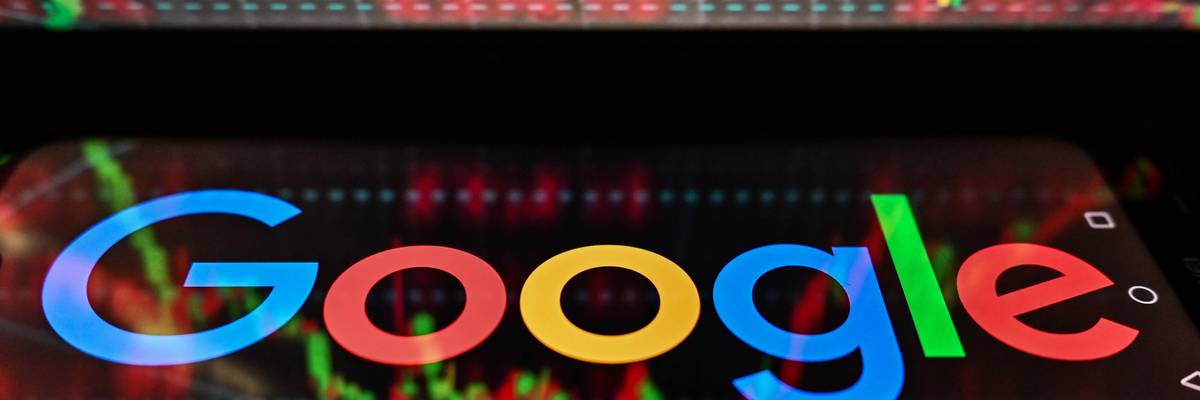 In this photo illustration, the Google logo seen displayed on a smartphone with stock market exchange in the background.