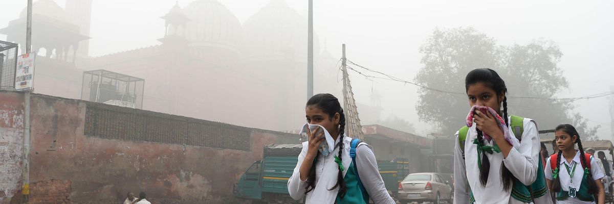 Indian students cover their faces as they walk to school amid heavy smog in New Delhi on November 8, 2017
