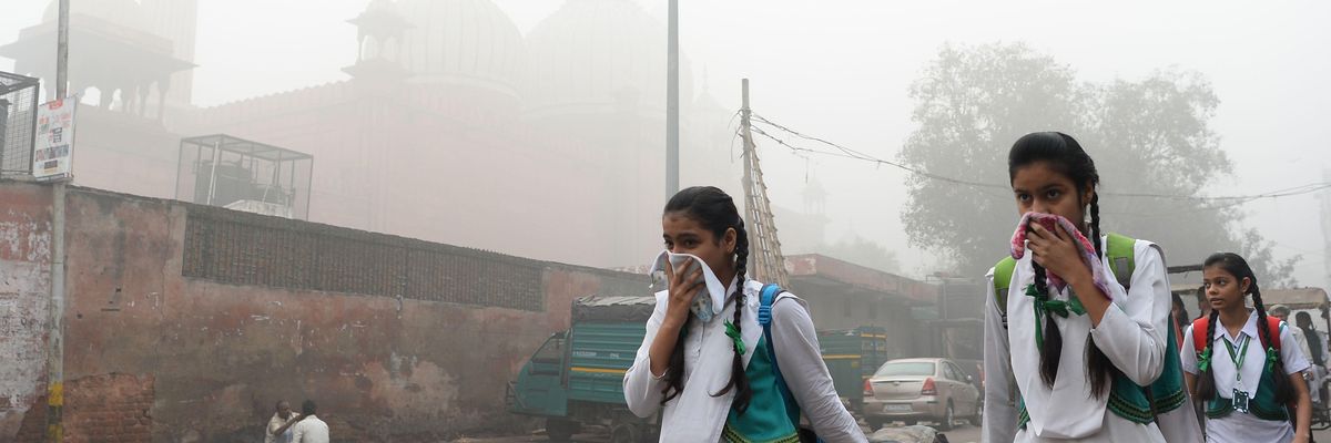 Indian students cover their faces as they walk to school amid heavy smog in New Delhi on November 8, 2017.
