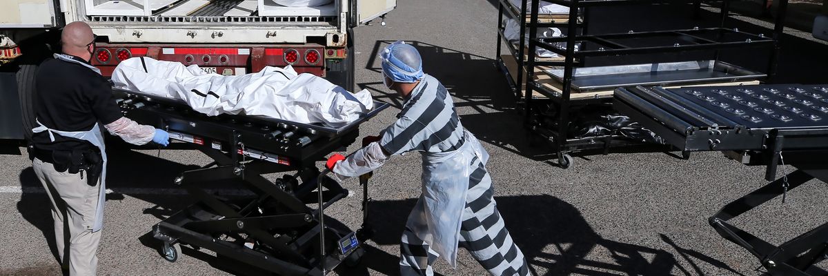 Inmate loads a body into a refrigerated temporary morgue truck during the Covid-19 pandemic