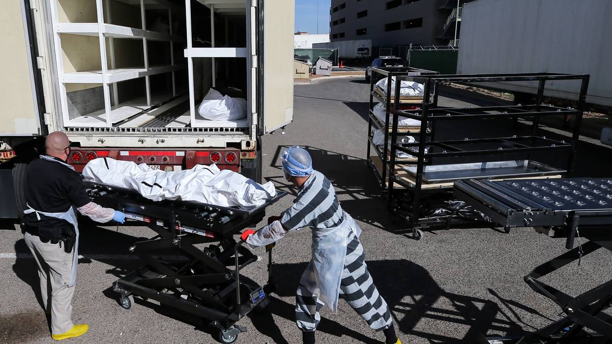Inmate loads a body into a refrigerated temporary morgue truck during the Covid-19 pandemic