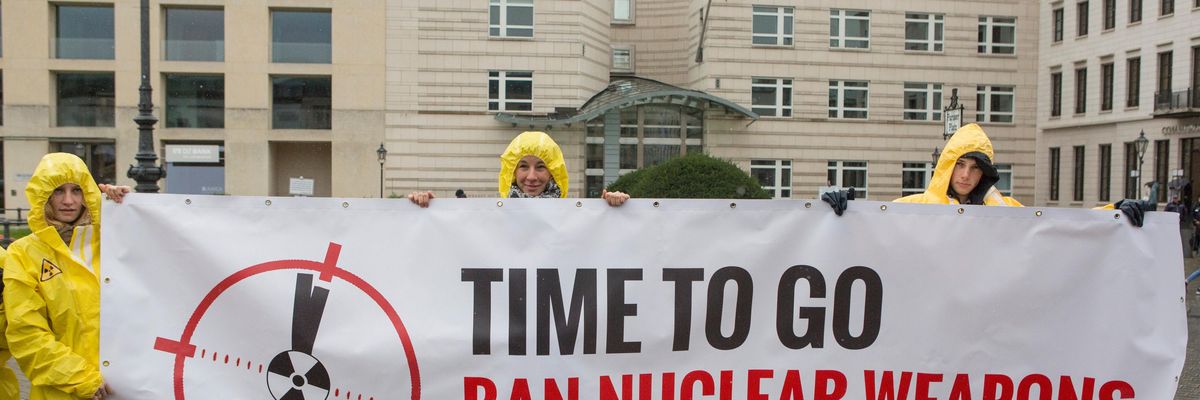 International campaign to abolish Nuclear Weapons (ICAN) activists wearing yellow hazmat suits and holding a banner reading 'Time to go, ban nuclear weapons'