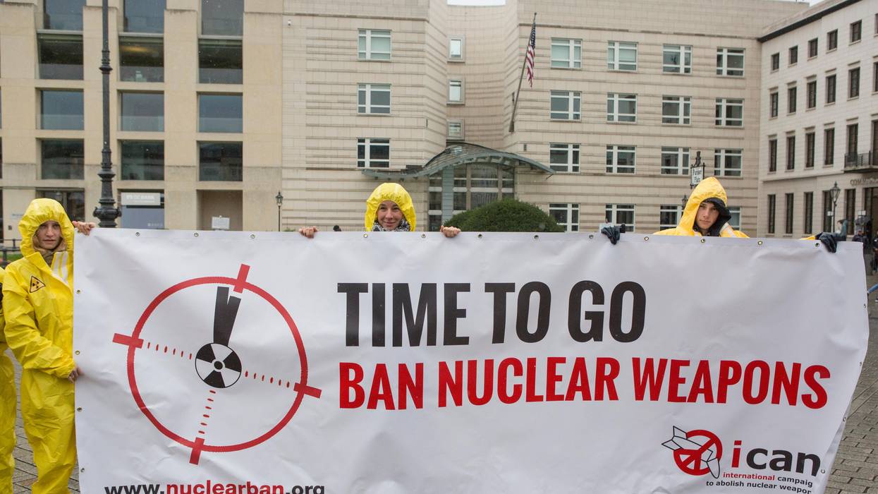 International campaign to abolish Nuclear Weapons (ICAN) activists wearing yellow hazmat suits and holding a banner reading 'Time to go, ban nuclear weapons'