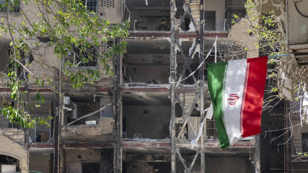 Iranian flag hangs from damaged building.