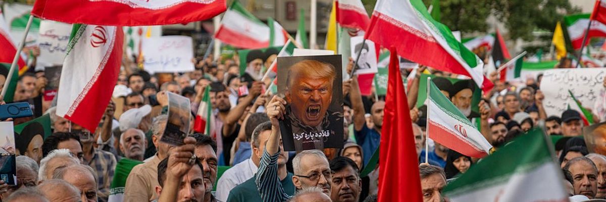 Iranian protesters chant slogans and one holds a poster with a vampire-like illustration of U.S. President Donald Trump