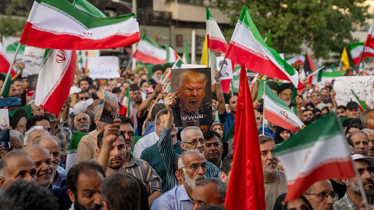 Iranian protesters chant slogans and one holds a poster with a vampire-like illustration of U.S. President Donald Trump