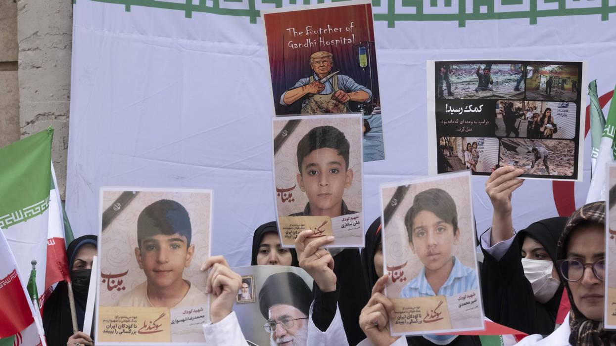 Iranian women hold up photos of children killed by US-Israeli attacks