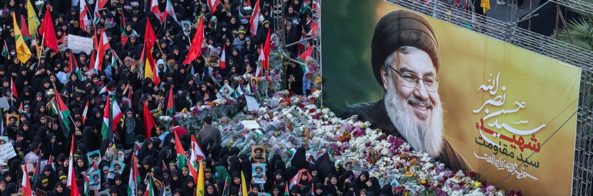 Iranians lay flowers beneath a billboard bearing a portrait of Hezbollah leader Hassan Nasrallah