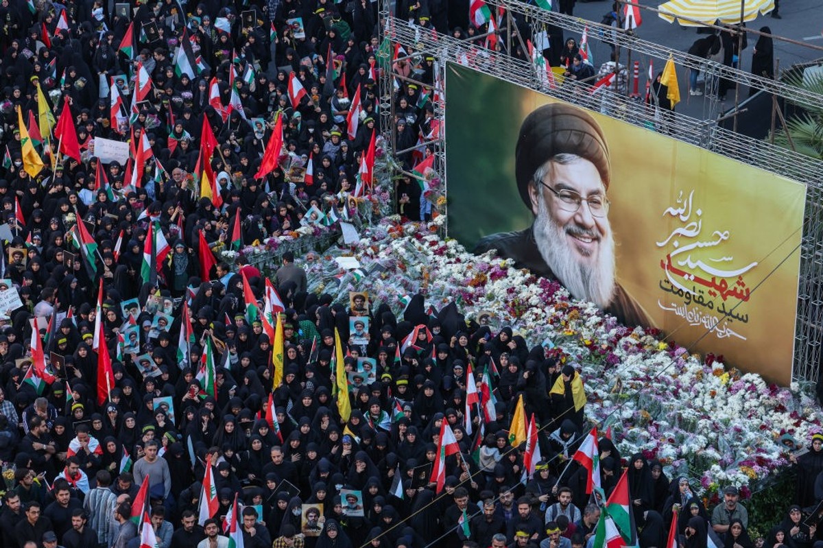 Iranians lay flowers beneath a billboard bearing a portrait of Hezbollah leader Hassan Nasrallah