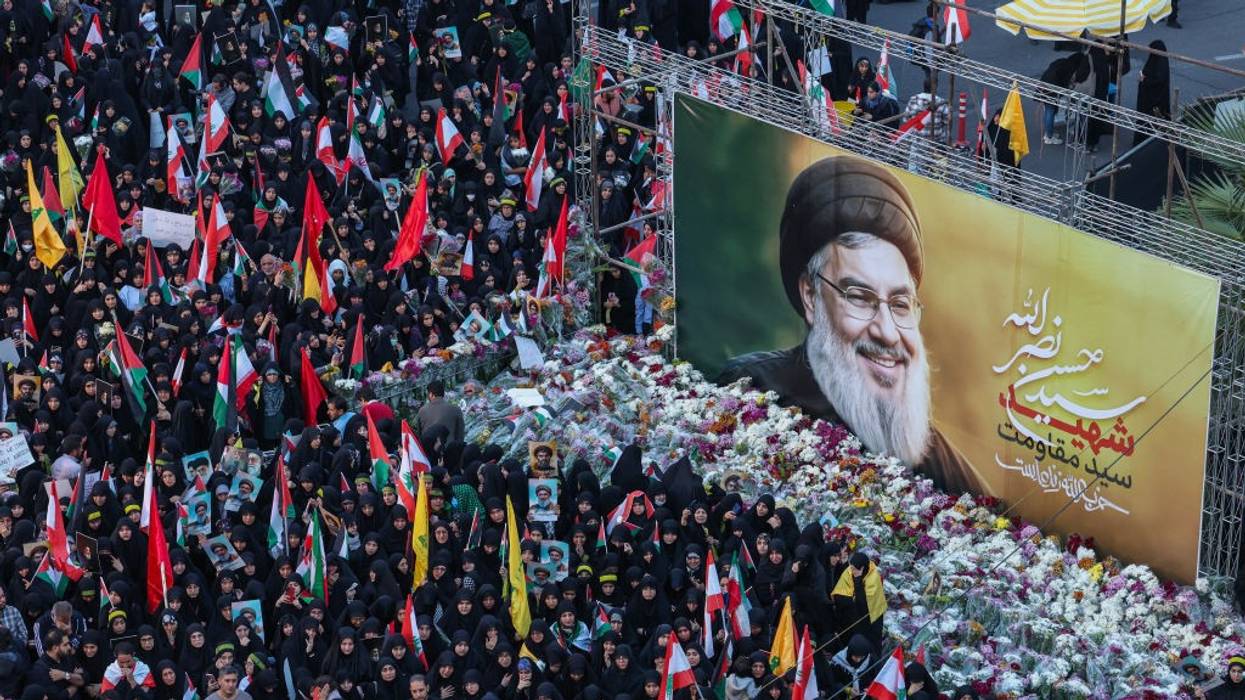 Iranians lay flowers beneath a billboard bearing a portrait of Hezbollah leader Hassan Nasrallah