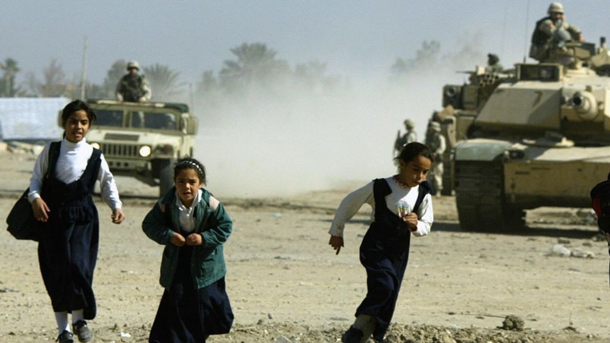 Iraqi schoolgirls flee an approaching US army patrol in the Baghdad suburb of Abu Gharib