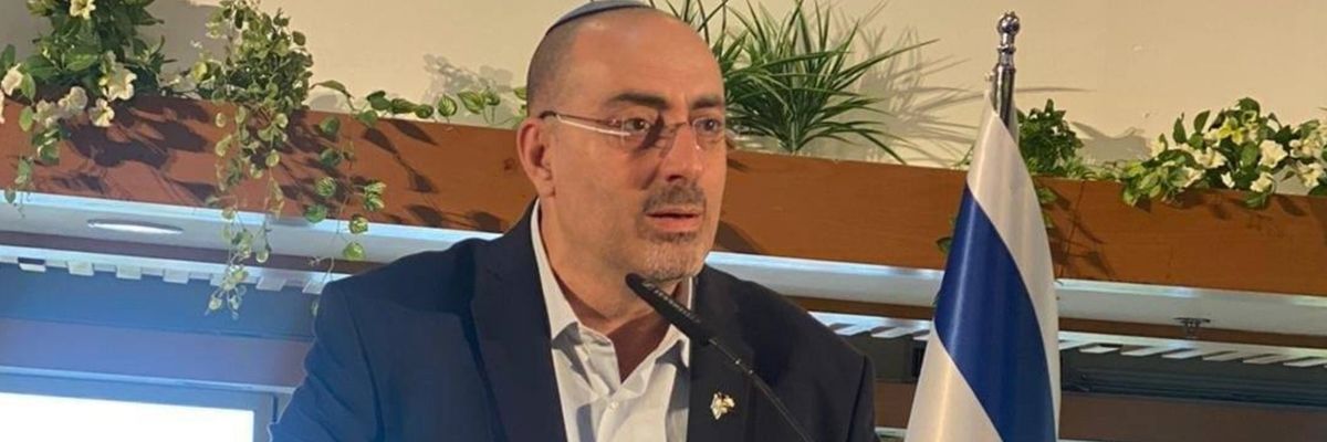 Israeli Deputy Knesset Speaker Nissim Vaturi delivers a speech beside an Israeli flag