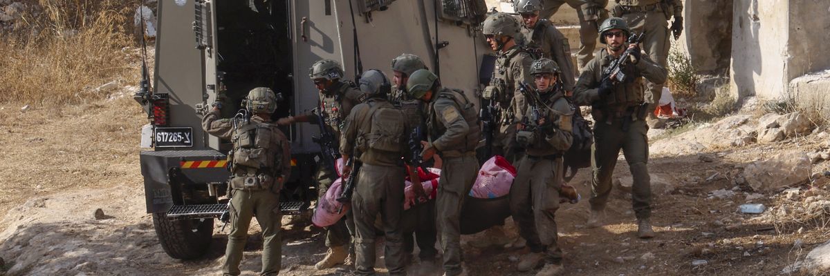 Israeli forces are pictured moving the body of a Palestinian man