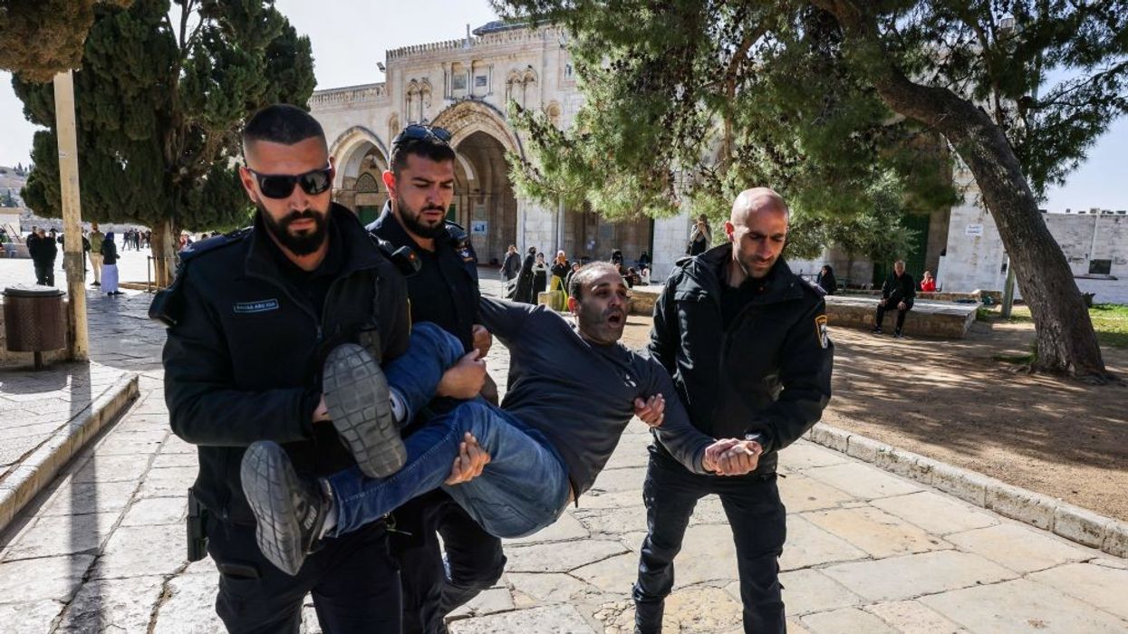 Israeli policemen detain a Palestinian man at the Al-Aqsa Mosque