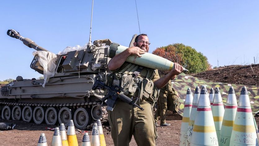 Israeli soldier grimaces while carrying 155mm artillery shell
