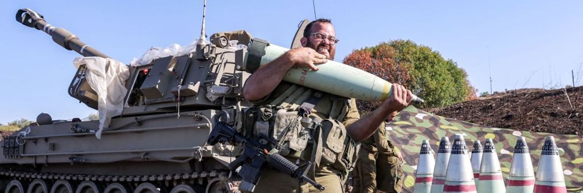 Israeli soldier grimaces while carrying 155mm artillery shell