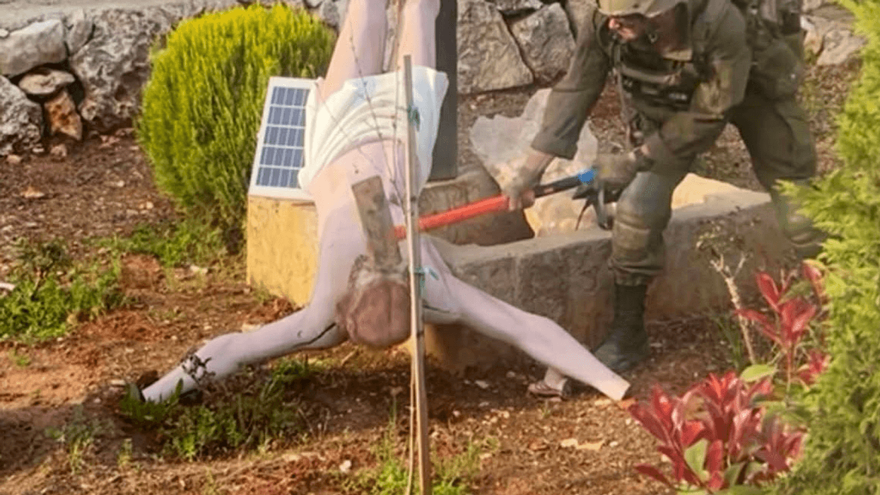 Israeli soldier smashes head of Christ statue.