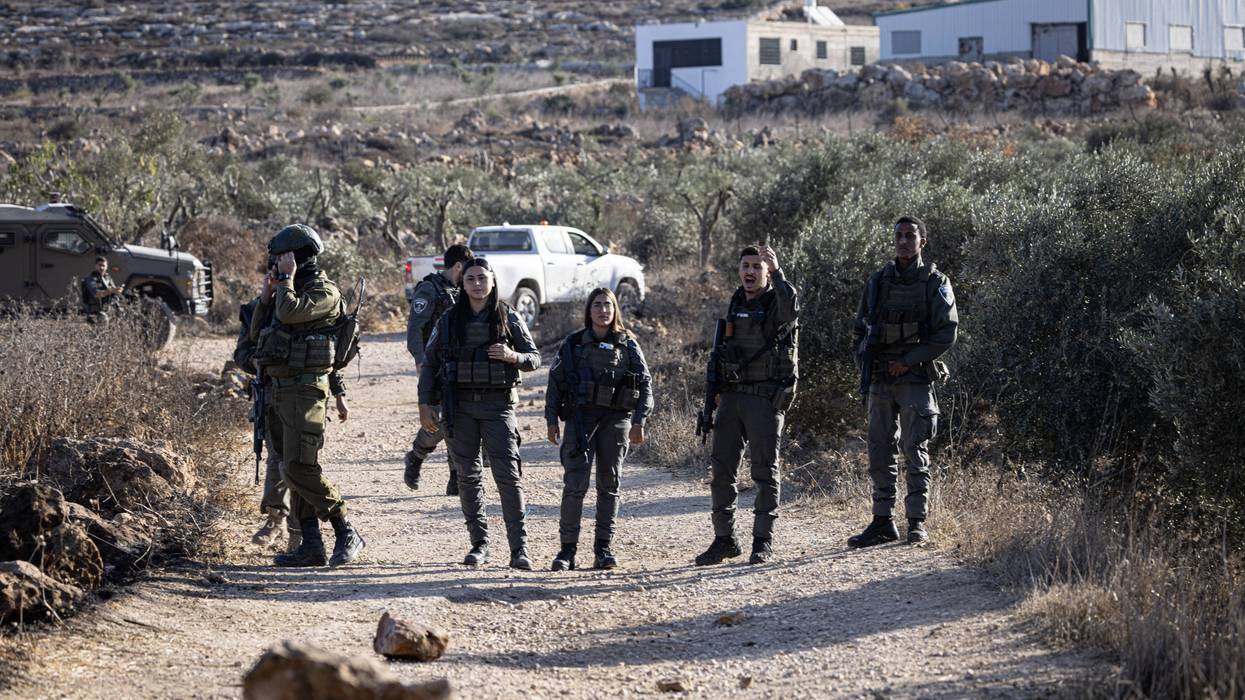 Israeli soldiers block the road to prevent Palestinian farmers from reaching their land
