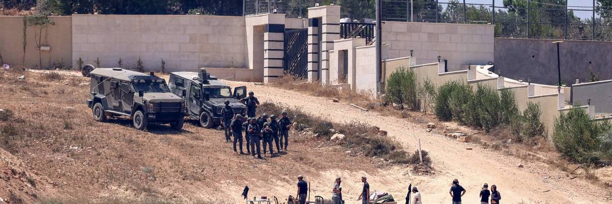 Israeli soldiers stand between settlers and Palestinian houses in the village of Qusra in the occupied West Bank on August 12, 2026.