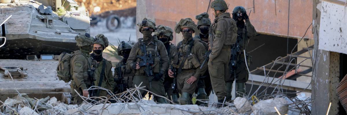 Israeli soldiers stand near a damaged building in southern Lebanon