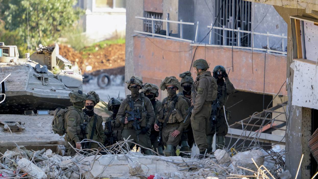 Israeli soldiers stand near a damaged building in southern Lebanon