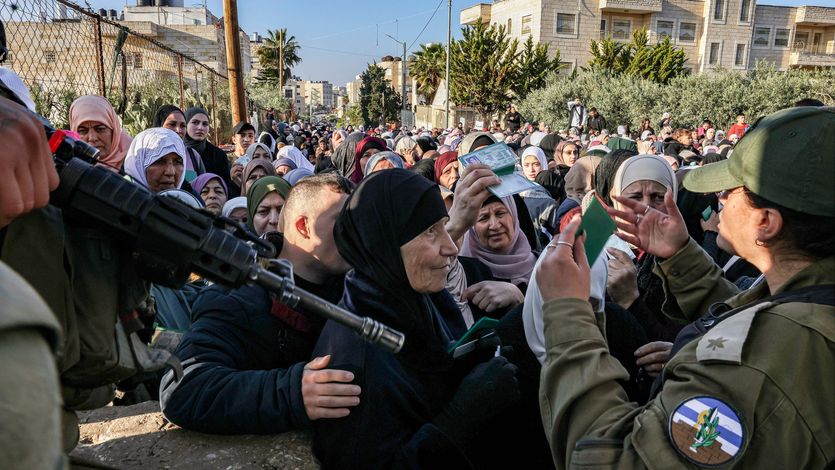 Israeli troops control a large group of Palestinian woman at gunpoint
