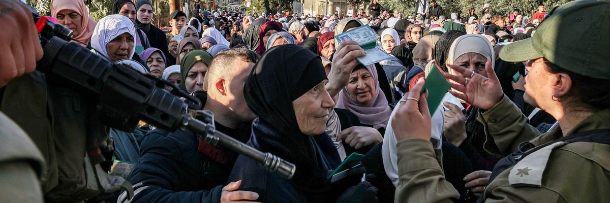 Israeli troops control a large group of Palestinian woman at gunpoint