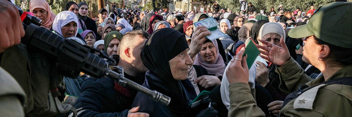 Israeli troops control a large group of Palestinian woman at gunpoint