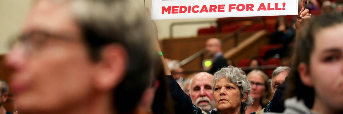 Jamie Sheldon holds a Medicare for All sign as she listens to House Speaker Nancy Pelosi (D-Calif.) address an audience during a town hall meeting on gun violence at Lincoln High School in San Francisco on August 27, 2019