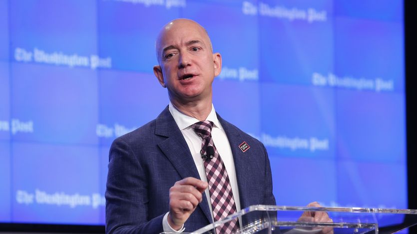 Jeff Bezos speaks against a blue background with Washington Post written in white letters.
