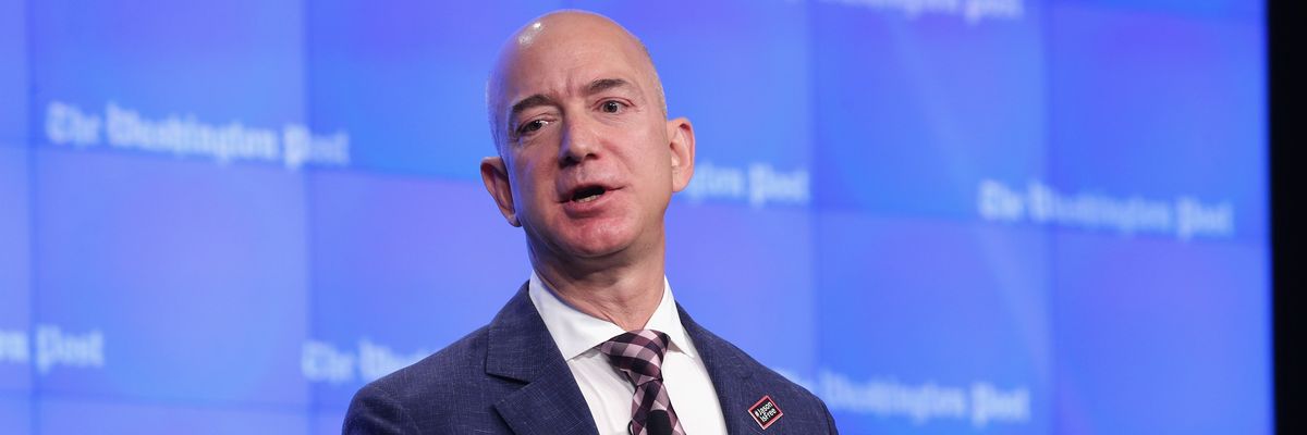 Jeff Bezos speaks in front of Washington Post logo.