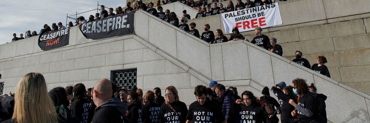 Jewish-led protesters in black t-shirts reading "not in our name" protest at the Statue of Liberty.