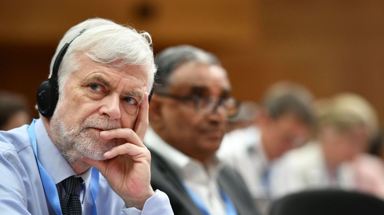 Jim Skea sits with headphones on and a hand on his chin.