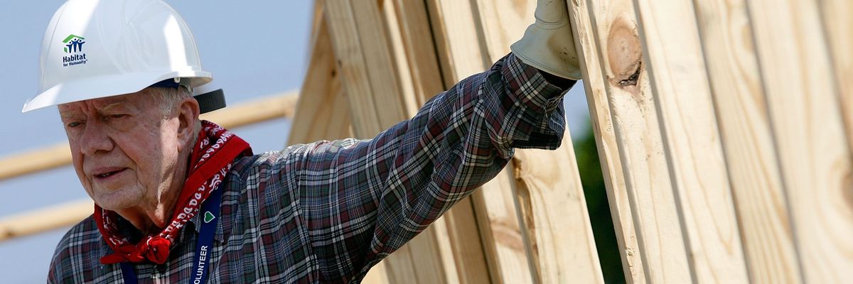 Jimmy Carter leans on the newly framed 1,000th home built by Habitat For Humanity on the Gulf Coast in Louisiana.
