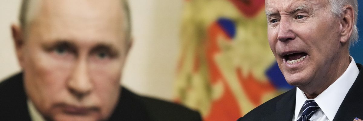 Joe Biden speaking in front of a photo of Vladimir Putin