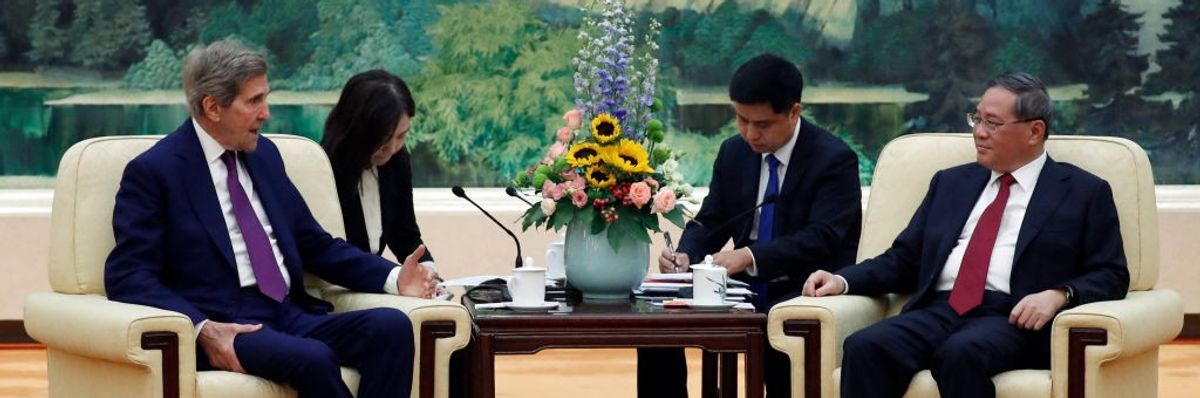 John Kerry and Li Quiang sit at a table. 
