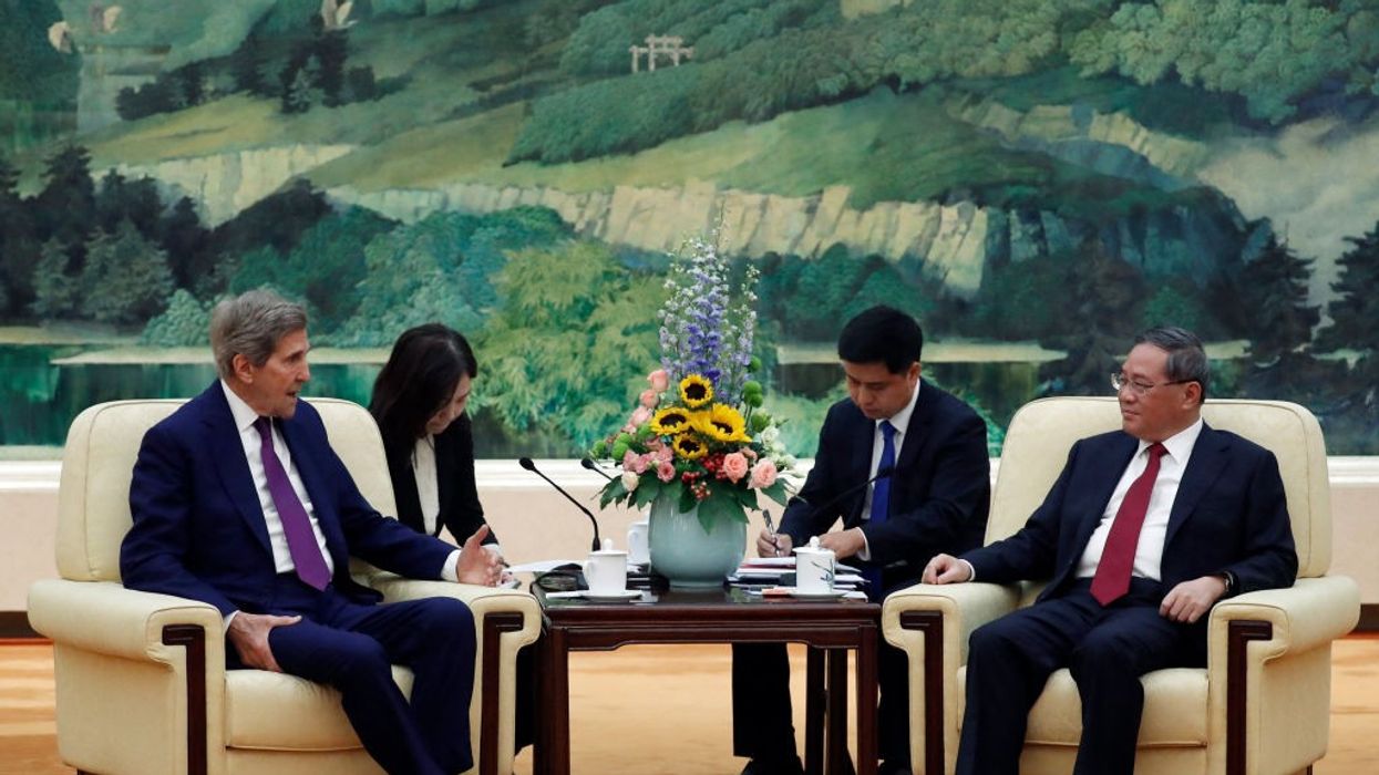 John Kerry and Li Quiang sit at a table.