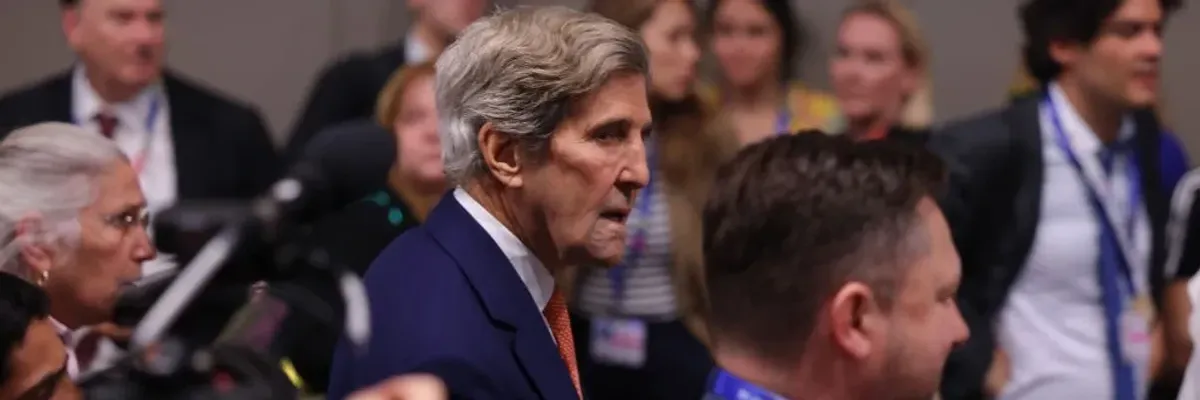 John Kerry walks through a crowd at COP28.