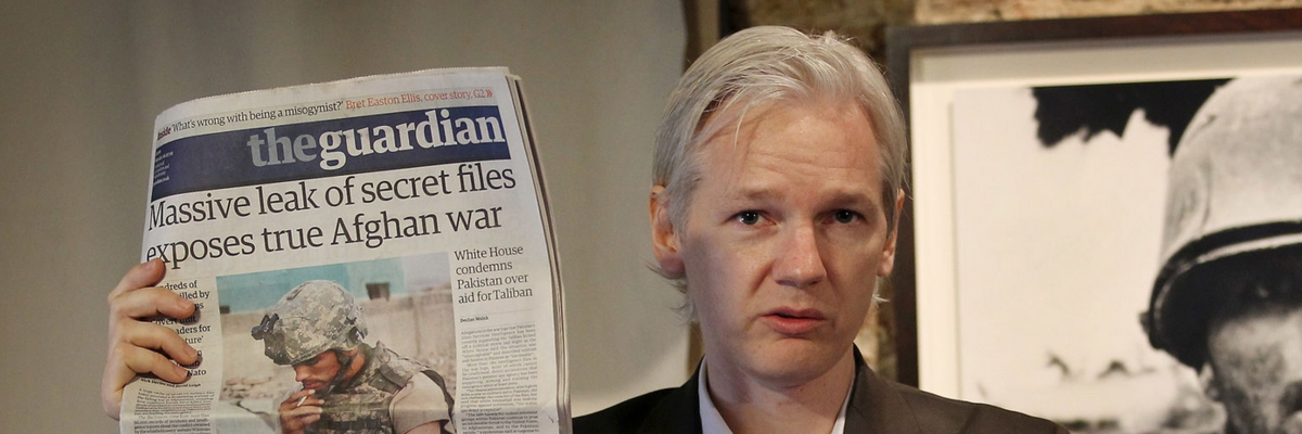 Julian Assange holds The Guardian.